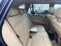 Interior view of a 2009 BMW X5 showing the rear seating area with beige leather seats and a silver item on the middle seat