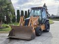 A 2005 Case 570 tractor with a front loader attachment in an orange and black color scheme