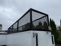 A black mesh safety cage atop a white utility vehicle designed for transporting equipment and materials
