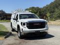 A 2022 GMC Sierra 1500 in white color with a truck bed cover and roof racks parked on a paved surface