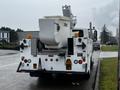 A 2013 International DuraStar bucket truck with an elevated bucket and various safety lights and markings on the rear side