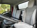 Interior of a 2016 Isuzu NPR featuring two grey upholstered seats with seatbelts and a steering wheel in the foreground