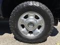 Close-up of a silver wheel with a rugged tire on a 2014 Ford F-250 SD showcasing its durable design and off-road capability