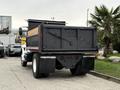A 2006 International 4200 dump truck with a black bed and wooden sides parked with an empty cargo area and visible rear lights