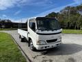 A white 2004 Toyota Toyoace flatbed truck facing forward with a clear view of the front and side features