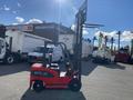 A red 2024 AGT KFE20 forklift with a raised mast and fork attachment standing on a paved surface