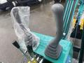 Two excavator control levers are positioned on a blue control panel with one lever covered in plastic and the other gray in color with a rubber grip