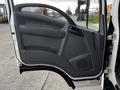 The image shows the interior side of a 2022 Isuzu NPR truck door with a gray panel and handle visible