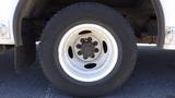 A close-up of a tire mounted on a white wheel from a 2011 Ford Econoline showing a rugged tread pattern and visible wear on the surface