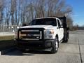 A white 2011 Ford F-350 SD truck with a flatbed and a black tool rack attached to the rear, featuring chrome accents and large wheels