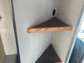 A storage cabinet with two triangular wooden shelves against a plain wall inside a vehicle