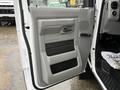 The interior door panel of a 2014 Ford E-450 featuring a gray design with a handle a speaker grille and armrest area