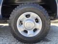 A close-up of a silver alloy wheel with a rugged all-terrain tire mounted on a 2014 Ford F-250 SD