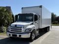 A white 2020 Hino 268 box truck with a chrome grille and large side mirrors parked with a straight truck bed and orange marker lights on the roof
