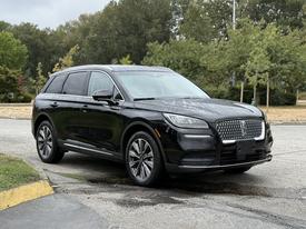 A 2020 Lincoln Corsair in black with a sleek design and chrome accents parked on a paved area with a clear view of its front and side features