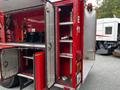 A red 1991 Sutphen Deluge fire truck with an open compartment revealing shelves and equipment including a hose nozzle