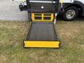 A yellow wheelchair ramp extended from the rear of a vehicle showing a textured surface for traction