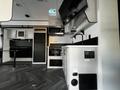 Interior view of a 2022 Heartland Torque camper featuring a kitchen area with appliances like a microwave stove and refrigerator along with cabinetry and a mounted television
