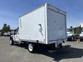 A 2008 Ford F-450 SD with a white box truck body and a rear loading door parked on a gravel surface