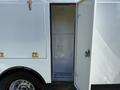 A 2023 Ford F-550 with an open side compartment showcasing a spacious interior with shelves and drainage system