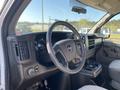 Interior view of a 2012 GMC Savana showing the steering wheel dashboard and center console with cup holders