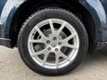 A close-up of a silver alloy wheel from a 2013 Dodge Journey showing a tire with treads and the wheel's lug nuts