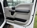 A close-up view of the driver's side door panel of a 2020 Ford F-550 featuring a gray and black interior design with a large handle and several storage compartments