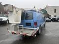 A blue 2009 Ford Econoline van with a mounted lift and a metal platform attached at the rear