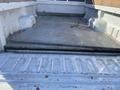 A 2000 Ford F-350 SD truck bed with a flat surface and some cargo tie-downs visible inside