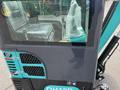 A 2024 AGT Industrial Green QH13R Mini Excavator showcasing a portion of its cab with protective plastic on the seat and control levers visible