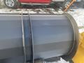 A 2000 plow with a 12-foot attachment featuring a cylindrical blade and metal construction designed for snow removal
