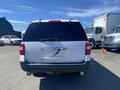 A white 2013 Ford Expedition viewed from the rear with a missing license plate and some wear on the bumper
