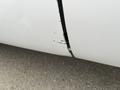 A damaged section of a white 2010 Ford F-250 SD showing scratches and a small gap in the bodywork