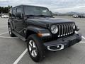 A black 2019 Jeep Wrangler with a distinctive front grille and round headlights parked in a lot