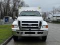 A white 2013 Ford F-650 with a large front grille and chrome accents is parked, facing forward with its headlights and large bumper prominently visible