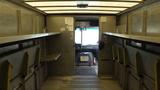 Interior view of a 2011 Ford Econoline showing empty shelves along the walls and a visible driver's seat area at the front