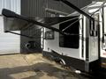 A 2021 Grand Design Recreational 311BHS with a black and white exterior and an extending awning on the side
