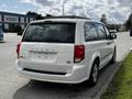 A white 2011 Dodge Grand Caravan parked with a view of its rear featuring the Dodge logo and a clean exterior without a license plate