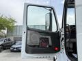 A 2012 Volvo VNL truck door is open showing the interior handle and speaker with a black panel featuring a red DG logo