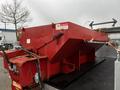 A red dump bed attached to a truck with warning labels and hydraulic controls visible on the side