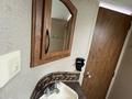A bathroom sink with a faucet and a mirror above it, accompanied by a black soap dispenser mounted on the wall
