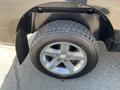 A close-up of a silver alloy wheel with a rugged tire on a 2011 RAM 1500 showcasing the wheel's design and tread pattern