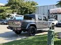 A 2021 Jeep Gladiator in gray with black rims parked at an angle showcasing its pickup truck design and distinctive Jeep logo on the tailgate