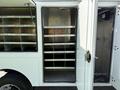 Interior view of a 2009 GMC C5500 service vehicle with open door revealing multiple metal shelves and storage compartments