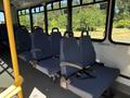 A row of blue upholstered seats with seatbelts inside a vehicle designed for passenger transport