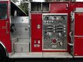 A red 1991 Sutphen Deluge fire truck with a polished silver panel displaying various gauges valves and nozzles designed for firefighting operations