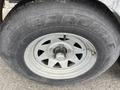 Close-up of a tire on a trailer featuring a silver metal wheel with a five-spoke design and the word "CARLISLE" prominently embossed on the sidewall of the tire
