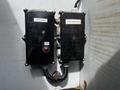 Two black electrical control boxes labeled Body Relays and Front Terminal Box connected by a cord mounted on a wall inside a vehicle