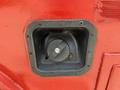 Fuel access cover of a 2013 Ford F-550 with a black circular cap and rectangular frame against a red surface