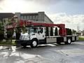 A 2010 International 4300 truck equipped with a red aerial lift extending from the bed of the vehicle